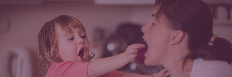 young girl playfully putting food in her mother's mouth